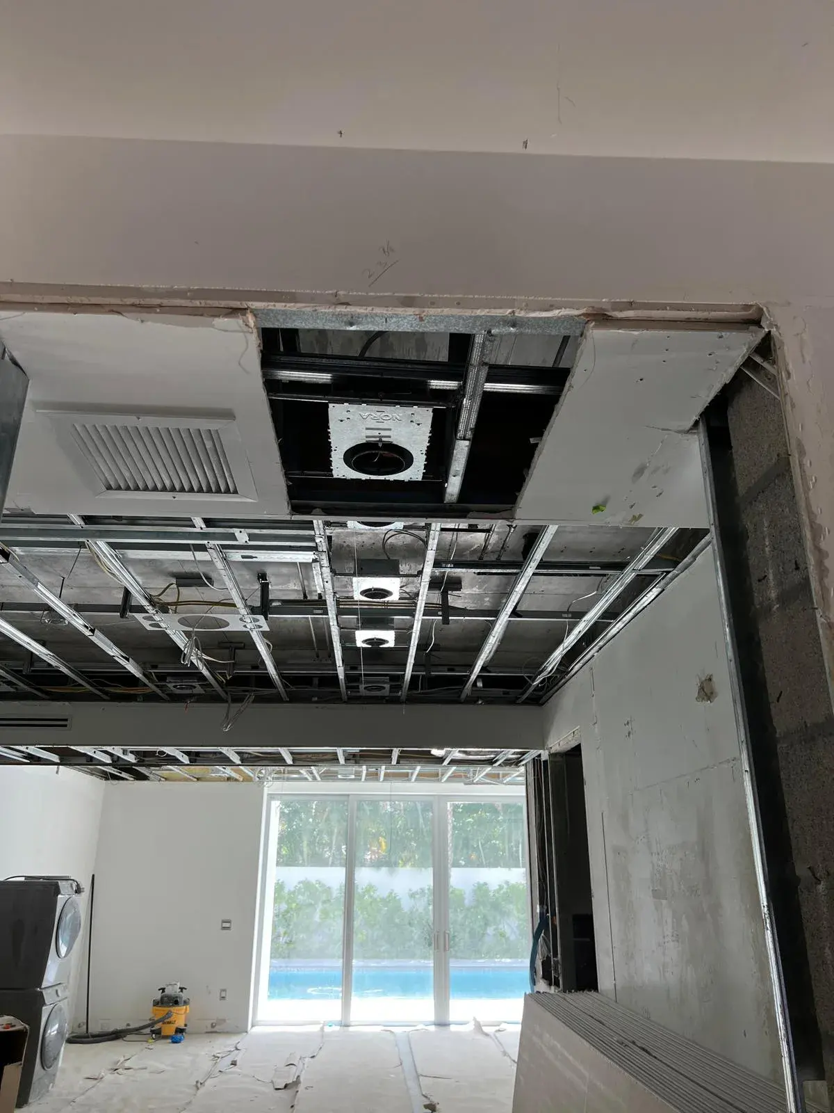 Open ceiling with a row of recessed light housings mounted on metal framing in a room under renovation